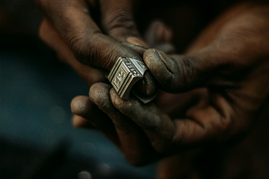 Mâini de meșter șlefuind manual o piesă mică de metal